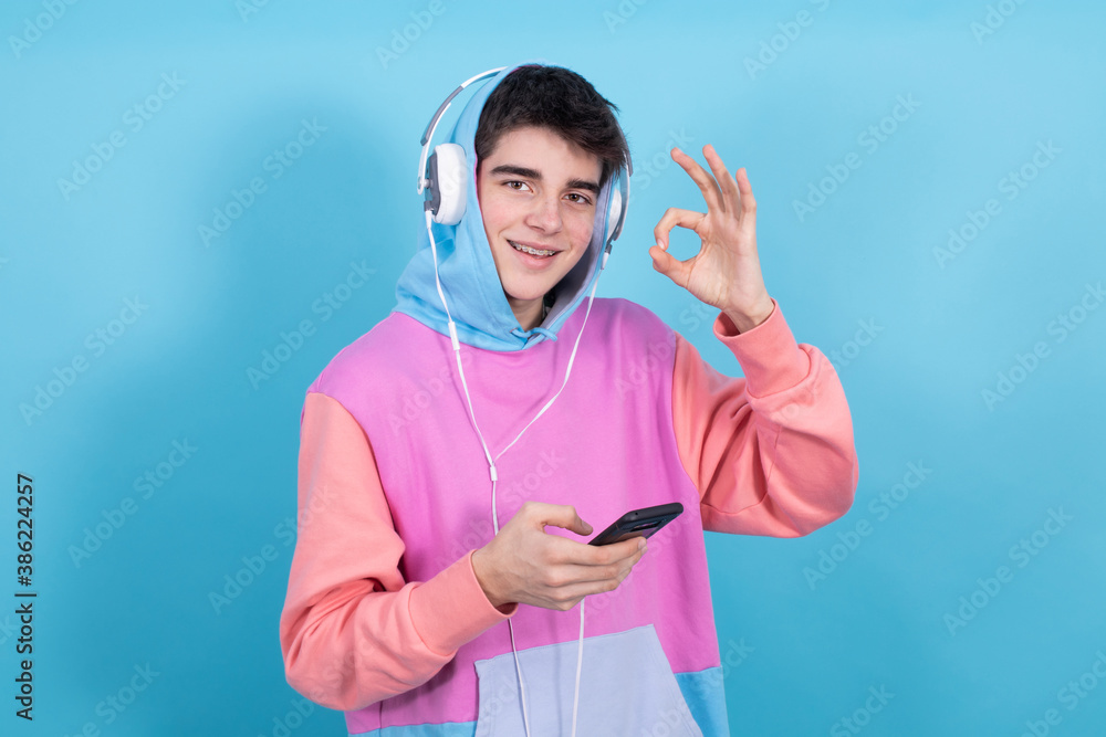 Wall mural teenager boy with mobile phone and headphones isolated on background