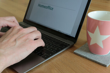 person typing on a laptop, cup