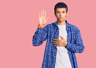 Young african amercian man wearing casual clothes swearing with hand on chest and open palm, making...