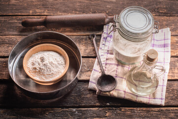 Flour in a jar, sifter, plunger and cooking oil on the kitchen table background.
