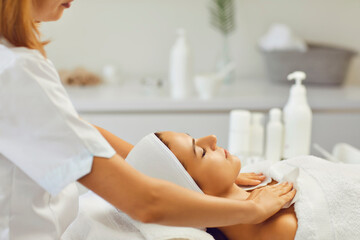 Cosmetologist wiping relaxing womans neck and shoulders after facial massage in spa salon
