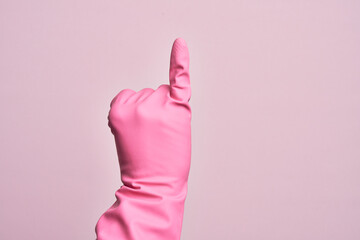 Hand of caucasian young man with cleaning glove over isolated pink background showing little finger...