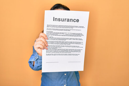 Woman holding insurance document paper standing over isolated yellow background