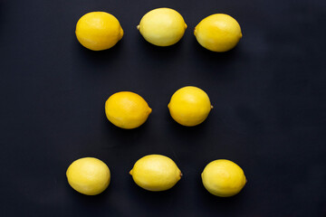 three rows of fresh lemons lie on a black background
