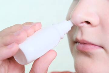 A boy with a runny nose holds a medicine in her hand, nasal spray irrigations to stop allergic...