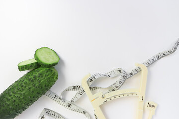 Fresh green sliced cucumber with a measuring tape and a caliper on white background as a concept of...
