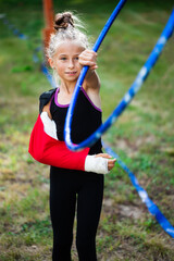 Girl gymnast in plaster cast on arm catching her hoop