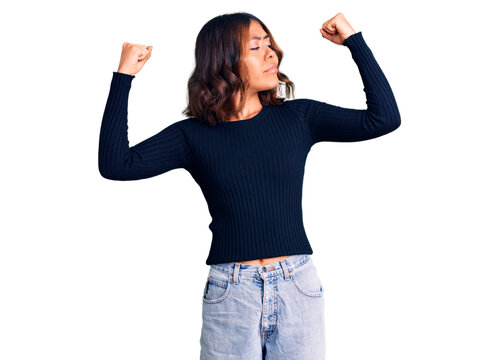 Young beautiful mixed race woman wearing casual clothes showing arms muscles smiling proud. fitness concept.