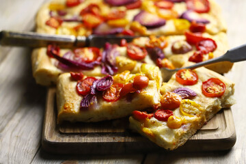Selective focus. Macro. Fresh homemade focaccia with tomatoes and blue onions. Italian cuisine at home. Focaccia recipe. Rustic style.