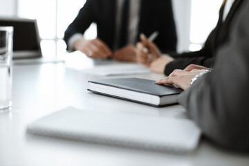 Unknown businessmen and woman sitting, working and discussing questions at meeting in modern office, close-up