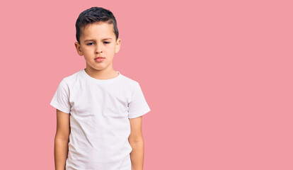 Little cute boy kid wearing casual white tshirt with serious expression on face. simple and natural looking at the camera.