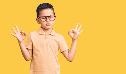 Little cute boy kid wearing casual clothes and glasses relax and smiling with eyes closed doing meditation gesture with fingers. yoga concept.