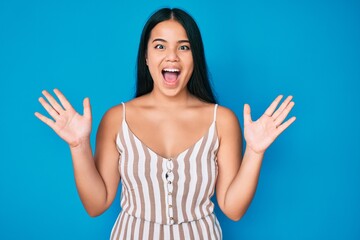 Fototapeta premium Young beautiful asian girl wearing casual clothes celebrating crazy and amazed for success with arms raised and open eyes screaming excited. winner concept