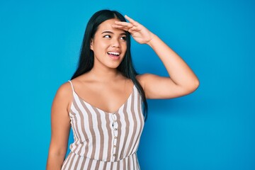 Young beautiful asian girl wearing casual clothes very happy and smiling looking far away with hand over head. searching concept.