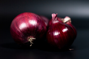 Two heads of red onions on a dark background.