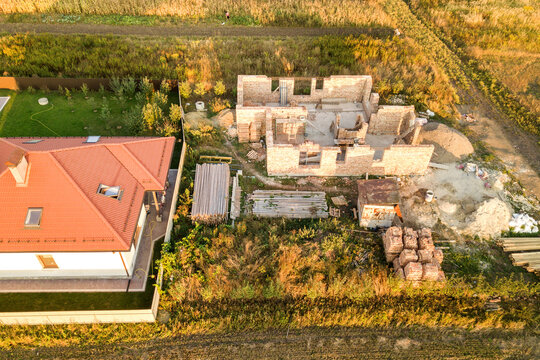 Top down aerial view of a house under construction with concrete foundament and brick walls.