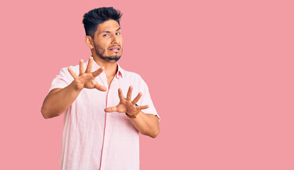 Handsome latin american young man wearing casual summer shirt afraid and terrified with fear expression stop gesture with hands, shouting in shock. panic concept.