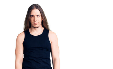 Young adult man with long hair wearing rocker style with black clothes and contact lenses with serious expression on face. simple and natural looking at the camera.