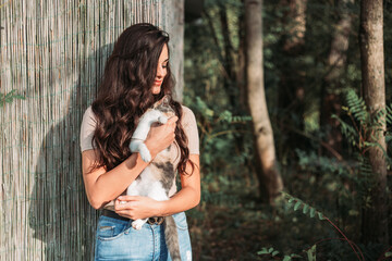 Beautiful young girl holding a calico cat. Outdoors photo, copy space