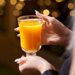 hands of girls holds a cup with warm yellow buckthorn tea inside