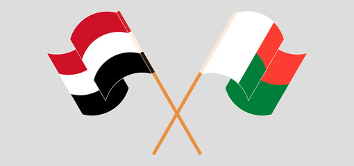 Crossed and waving flags of Madagascar and Yemen