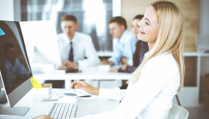 Business woman looks happy and excited at workplace in modern office. Secretary or female lawyer working for pleasure and success