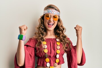 Young blonde girl wearing bohemian and hippie style screaming proud, celebrating victory and success very excited with raised arms