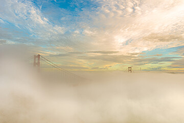 golden gate bridge under heavy fog in a sunny day at golden hour