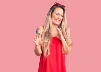 Young beautiful blonde woman wearing sleeveless t-shirt and sunglasses disgusted expression,...