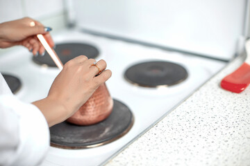 coffee is prepared in a coffee pot (cezve) on a white stove. small focus area, selective focus