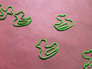 green paper clips in the form of ducks on craft background