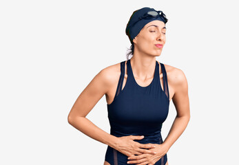 Young beautiful hispanic woman wearing swimwear and swimmer glasses with hand on stomach because indigestion, painful illness feeling unwell. ache concept.