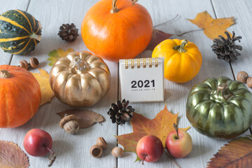 Calendar for 2021 and various autumn pumpkins on a light background for Halloween.