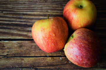 Close up and overhead view, red and yellow apples with drops of water, on rustic wood