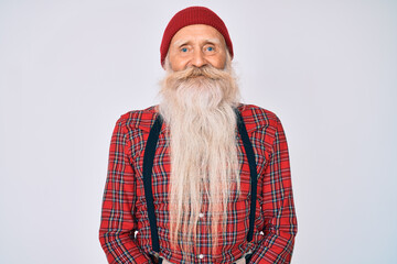 Old senior man with grey hair and long beard wearing hipster look with wool cap with a happy and cool smile on face. lucky person.