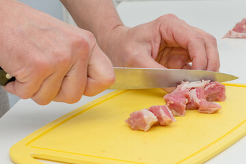 Close-up of a man's hand cutting fresh meat with a sharp knife on a cutting Board.Concept of cooking meat dishes, cooking, helping your wife in the kitchen, man cooking