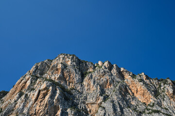 The tops of the yellow peaks of the rocks. Red stones on a blue background. Gray rocks at high altitude. Alps top on blue sky. Rough rocky stones.