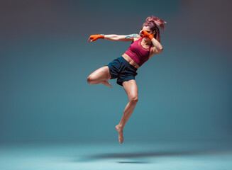 A young female fighter performs a jump kick.