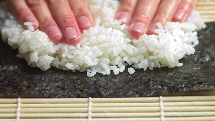 Spreading Cooked Sushi Rice On A Seaweed Wrap - Sushi Making - close up, slow motion.Sushi Chef Spreading Japanese Sushi Rice On Nori Sheet For A Delicious Sushi Rolls high angle shot