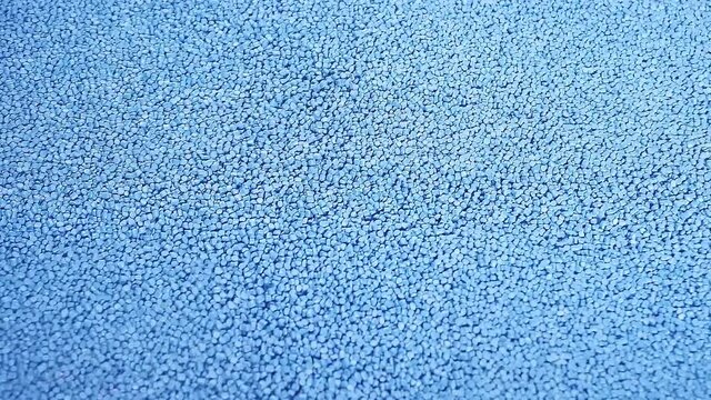 blue small plastic granules flow down the belt