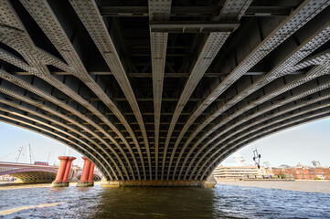 Beneath Blackfriars Railway Bridge in London, UK. The steel beams hold the structure in place with the Blackfriars station above. Also Blackfriars Road Bridge, St Pauls Cathedral and River Thames.