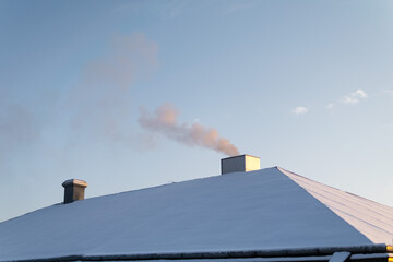 The smoke comes from the chimney. smoke billowing. coming out of a house chimney at winter