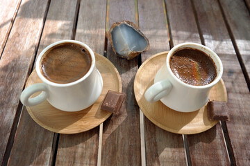 Turkish coffee with foam on top , made of fresh roasted and fine ground coffee beans, served in small ceramic cups on bamboo plates with Turkish delight or bitter chocolate pieces after breakfast