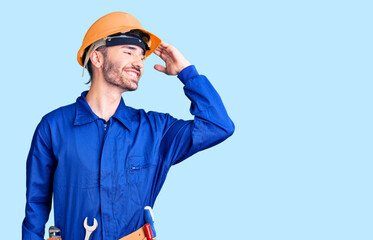 Young hispanic man wearing worker uniform smiling confident touching hair with hand up gesture, posing attractive and fashionable