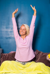 young blond woman stretching and yawing at home in the morning. Morning routines and  well being habits concept