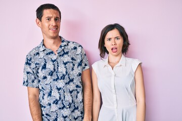 Beautiful couple wearing casual clothes in shock face, looking skeptical and sarcastic, surprised...