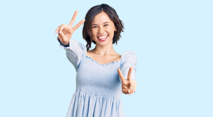 Fototapeta na wymiar Young beautiful girl wearing casual clothes smiling with tongue out showing fingers of both hands doing victory sign. number two.