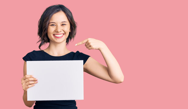 Young beautiful girl holding blank empty banner pointing finger to one self smiling happy and proud