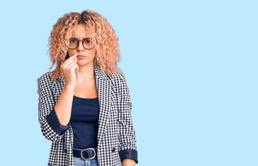 Young blonde woman with curly hair wearing business jacket and glasses mouth and lips shut as zip...