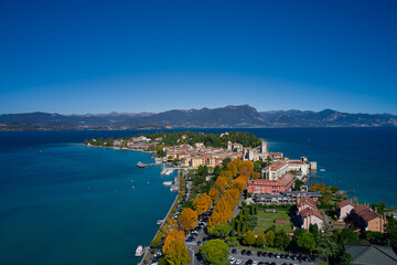 Fototapeta na wymiar Top view of the town of Sirmione, Italy. Autumn in Italy on Lake Garda, Sirmione peninsula. Trees in the autumn season. Lake Garda, a tourist destination in northern Italy.